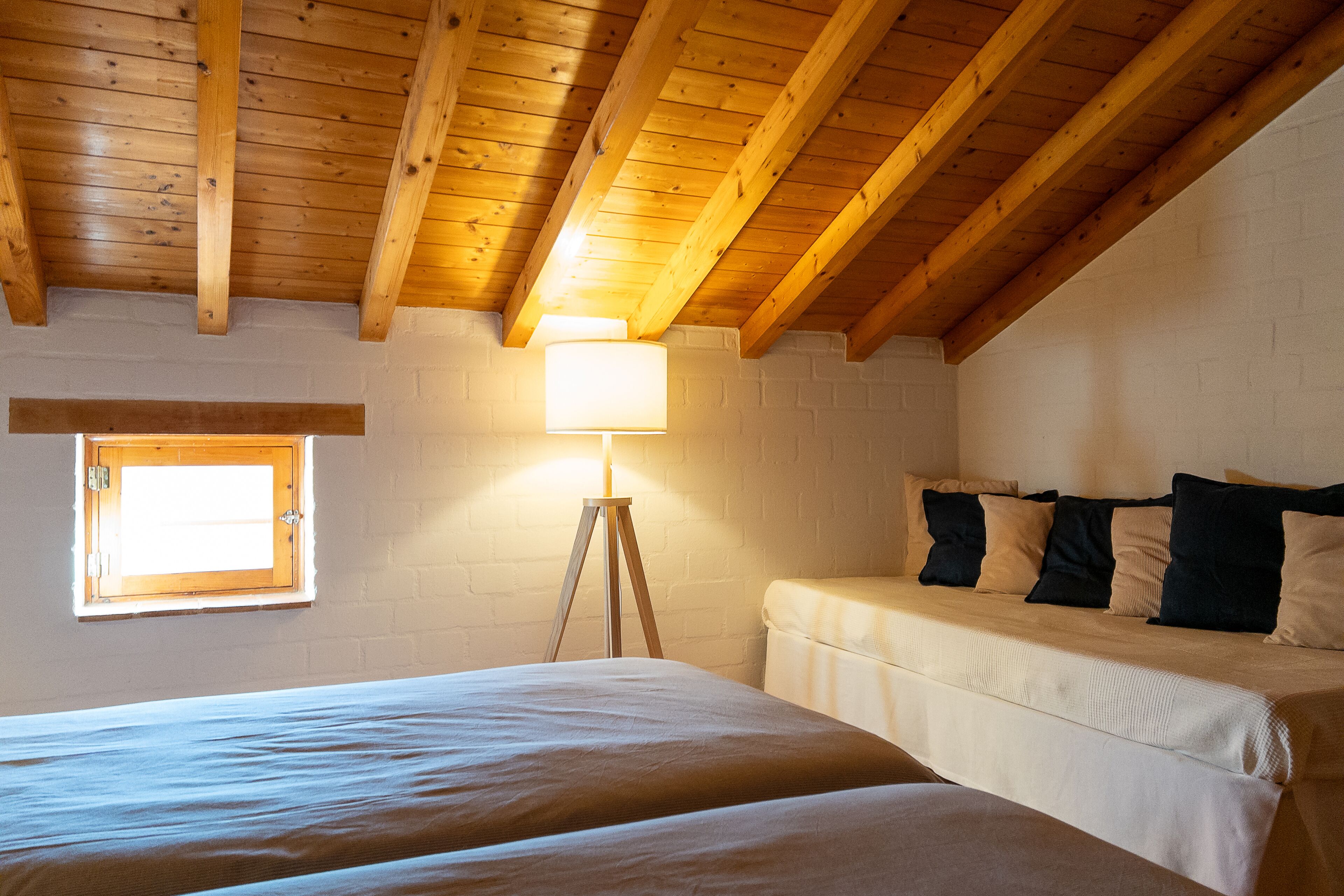 Un dormitorio con dos camas, una ventana y una lámpara.