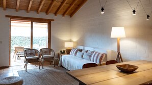 Ein gemütliches Zimmer mit Holzbalkendecke, einem Bett, einem Esstisch und einer Lampe.
