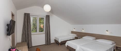 Un dormitorio con dos camas, un escritorio, un televisor y una ventana con cortinas.