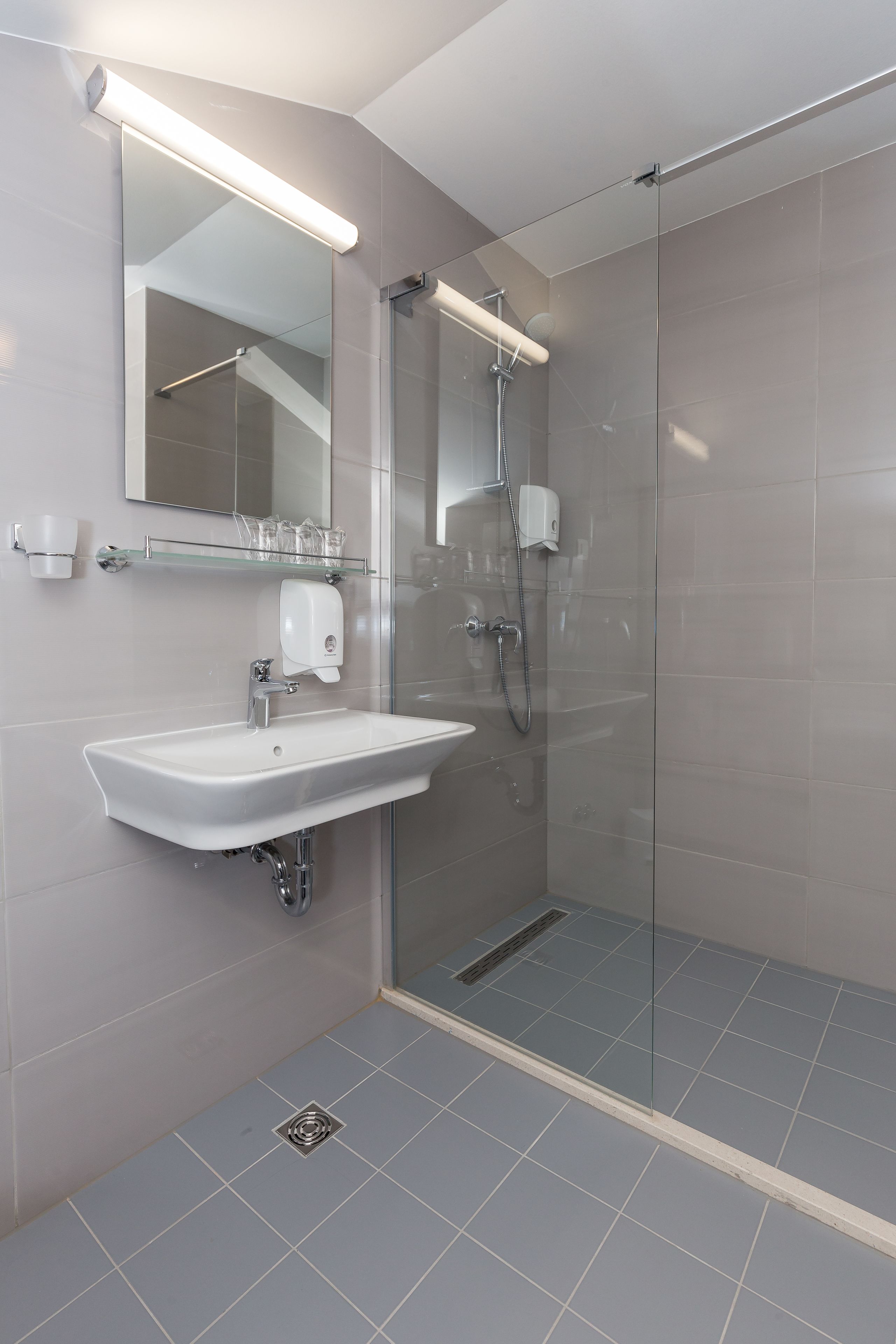 A modern bathroom with a glass-enclosed shower, a white sink, and a mirror above it.
