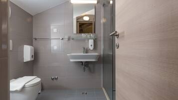 Une salle de bain moderne équipée de toilettes, d’un lavabo et d’une douche à parois de verre.