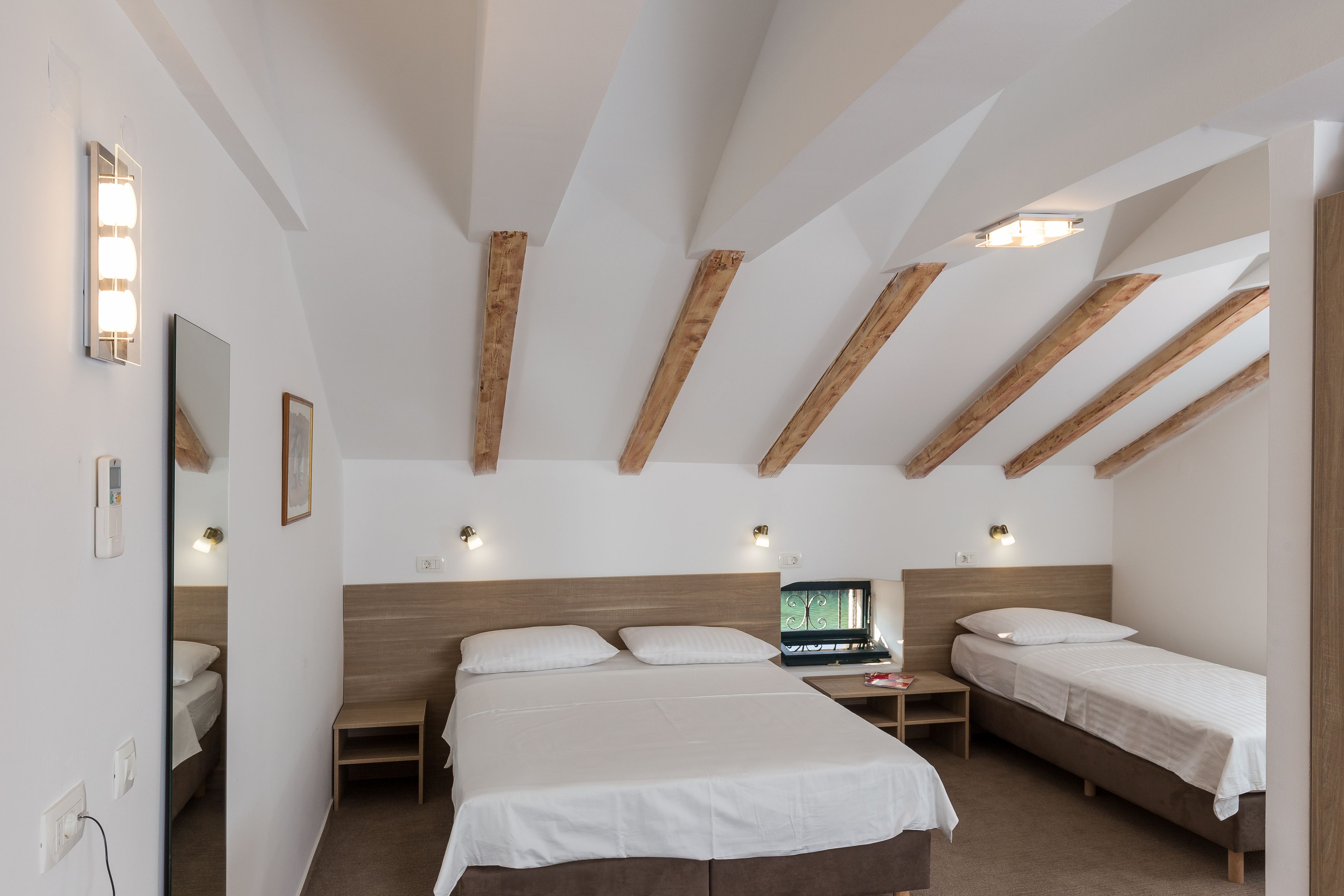Une chambre à coucher avec un grand lit, deux tables de chevet, un ordinateur portable et une structure de plafond en bois.