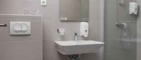 A modern bathroom with a toilet, sink, and glass shower enclosure.