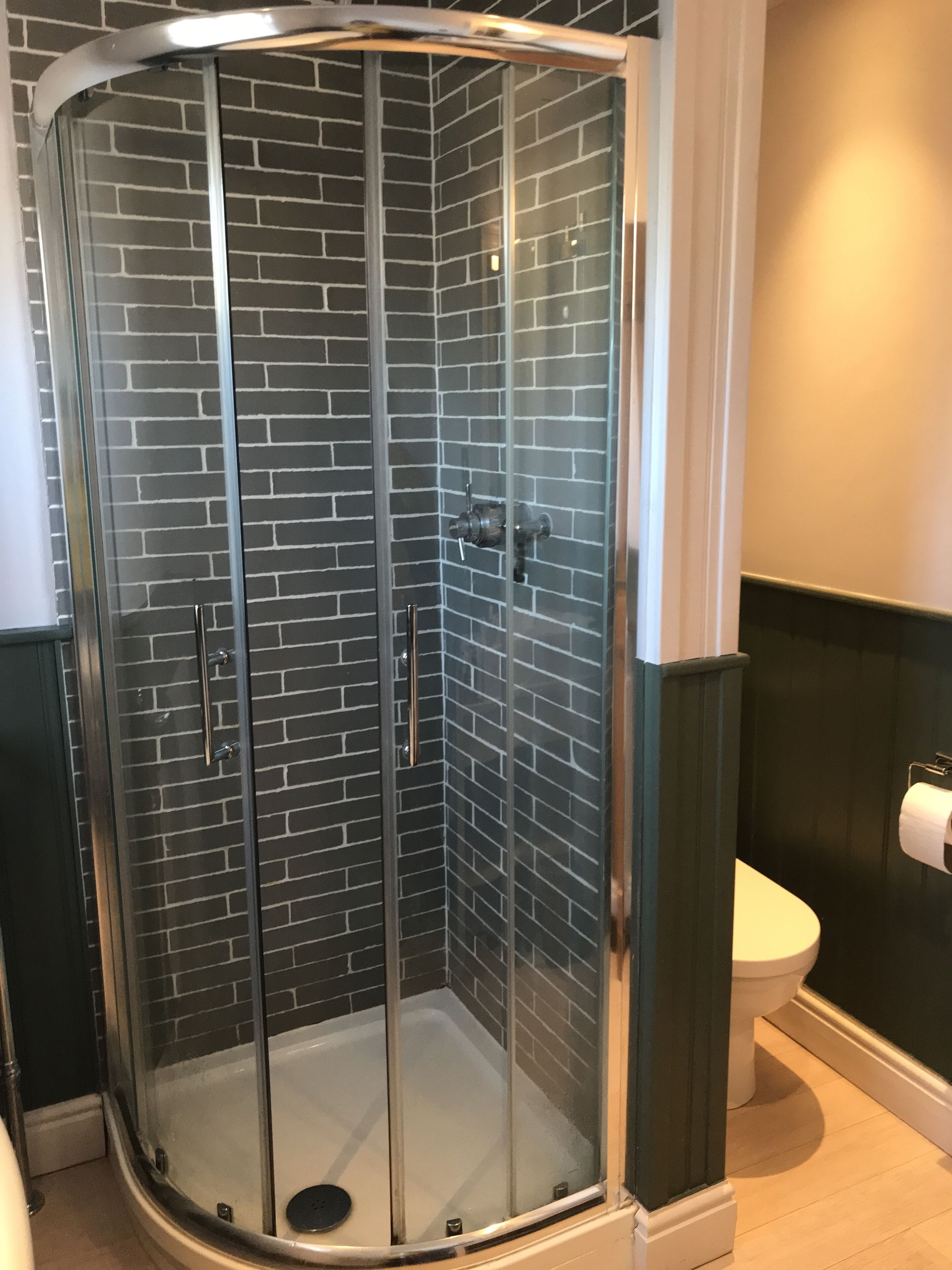 Een douchecabine met glazen deuren en een betegelde wand.