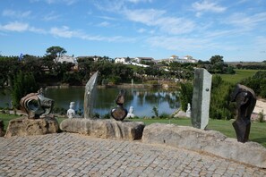 Un parc agrémenté de sculptures, d’un étang et de bâtiments en arrière-plan.