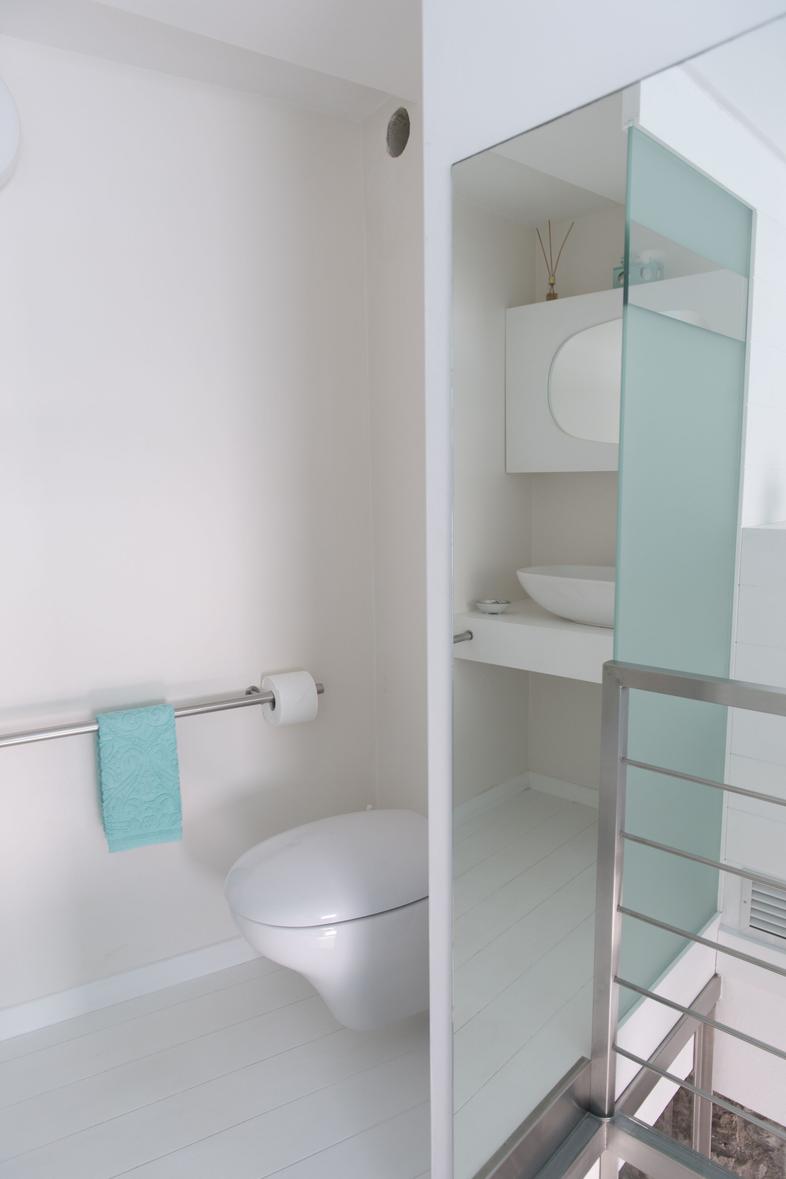 A modern bathroom with a glass shower enclosure, a white toilet, and a glass partition.
