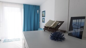 Een moderne kamer met een wit bureau, een blauwe decoratieve plant en een ingelijste foto aan de muur.