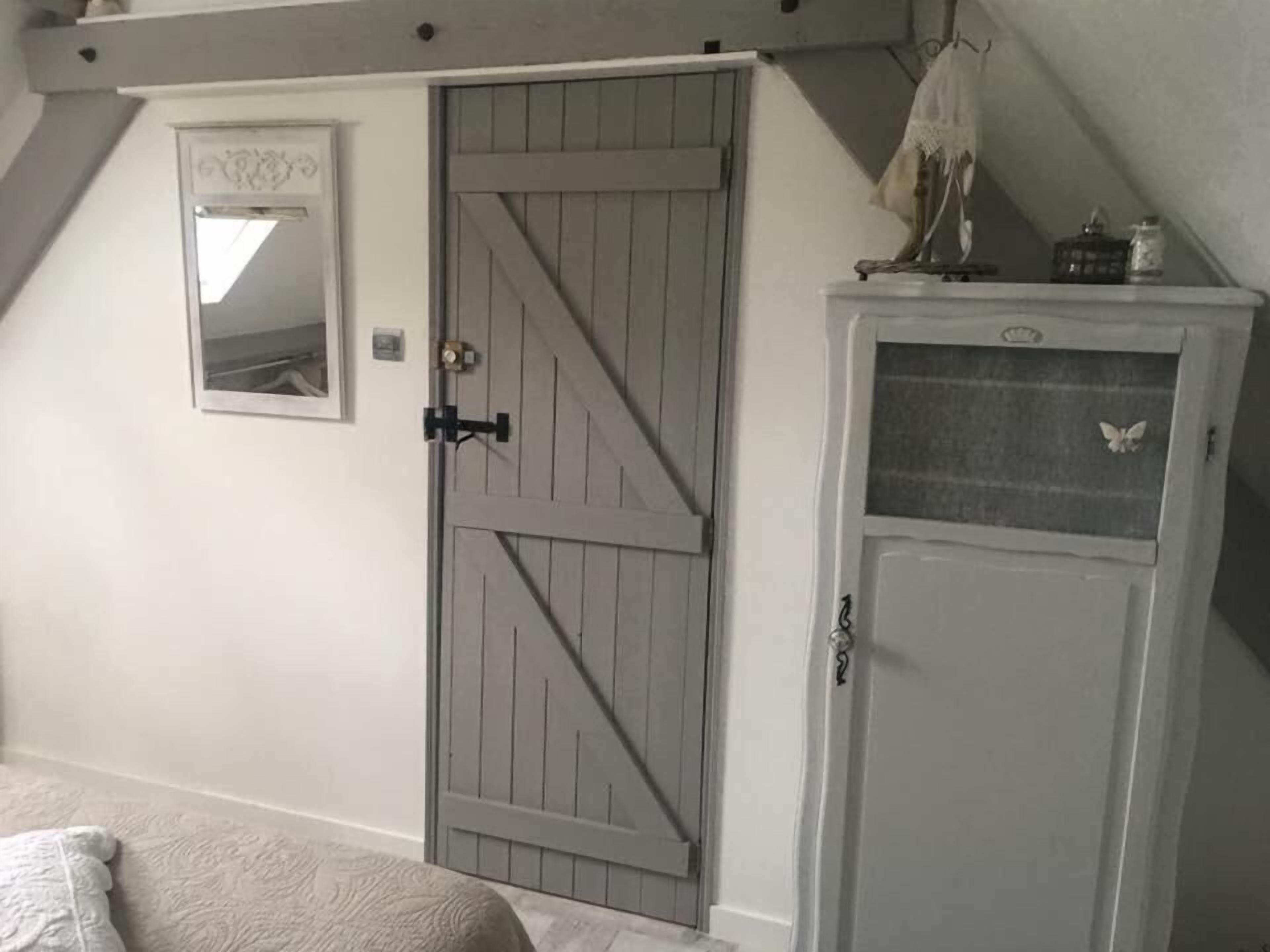 A bedroom with a large wardrobe, a door with a mirror, and a small cabinet with a butterfly decoration.