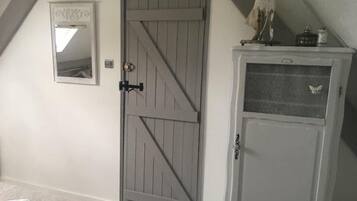 A bedroom with a large wardrobe, a door with a mirror, and a small cabinet with a butterfly decoration.
