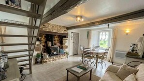 Una sala de estar acogedora con chimenea de piedra, una mesa de comedor con sillas, un sofá y una escalera.
