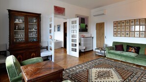 Una sala de estar con un sofá verde, un mueble de madera y una alfombra estampada.