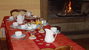 Une table à manger dressée pour le petit-déjeuner, avec une cheminée en arrière-plan.