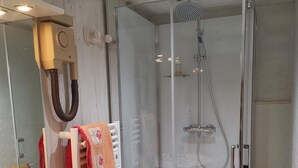 Une salle de bain moderne avec une douche à parois de verre, un lavabo blanc et un miroir doté d’un porte-serviettes.