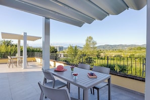 Un balcon avec une table et des chaises, une vue sur la campagne et une structure en forme de pergola.