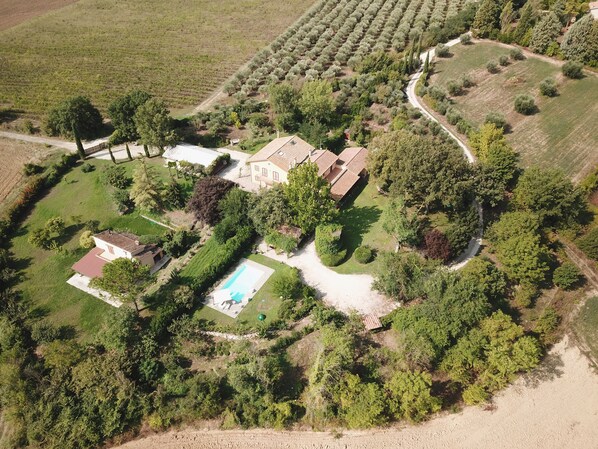 Vista aérea de una propiedad con una casa grande, piscina y jardines circundantes.