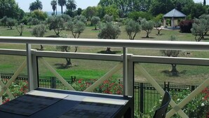 A view from a balcony with a table and chairs, overlooking a park with trees and a gazebo. - 2 bedroom, Overlooking Parc Exflora + Sea views. Pool+Beach 200m + Parking + A/C (Antibes)
