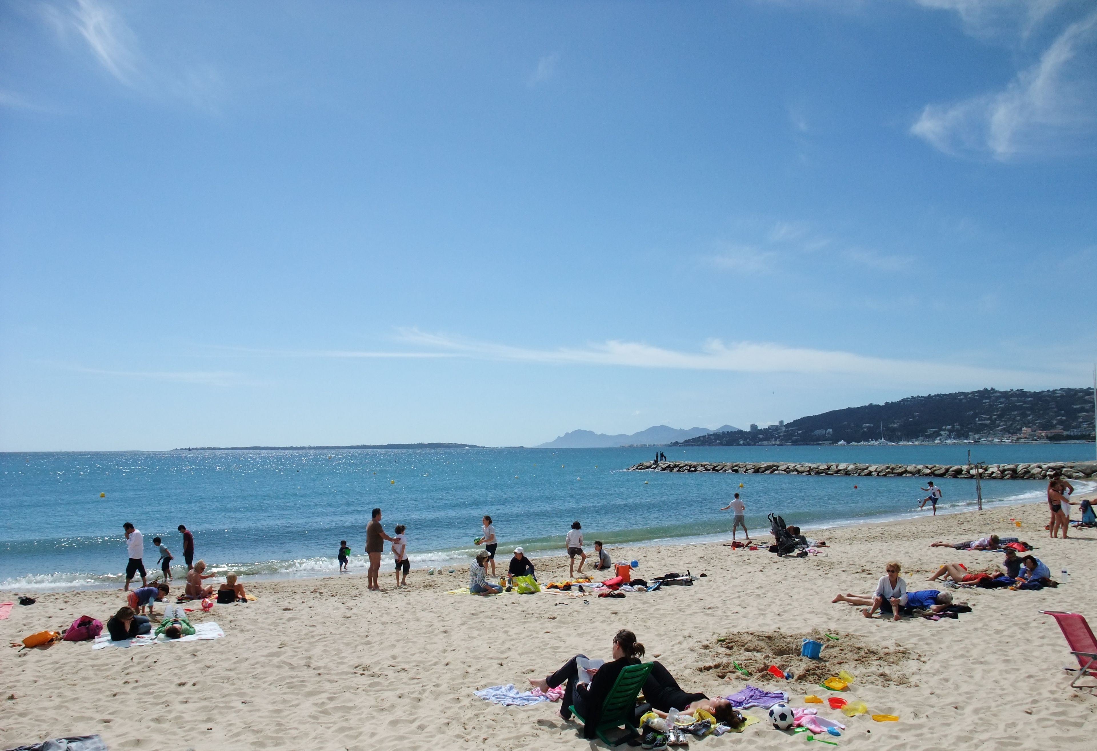 Una playa con gente tomando el sol y jugando.