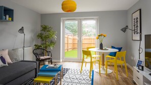 A modern living room with a grey sofa, yellow chairs, a white table, and a yellow pendant light. - Deco Spacious Townhouse (Coventry)