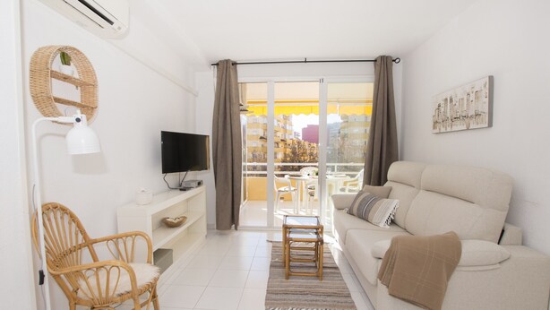 A modern living room with a sofa, a chair, a TV, and a balcony with a view of buildings. - A94 APOLO 7 ESC 6 3º 14 (Calpe)