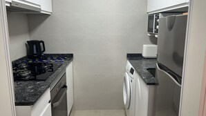 A compact kitchen with a gas stove, a coffee maker, a washing machine, and a microwave. - A94 APOLO 7 ESC 6 3º 14 (Calpe)