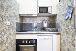 A kitchen with patterned tiles, a microwave, a sink, a stove, and a dishwasher.