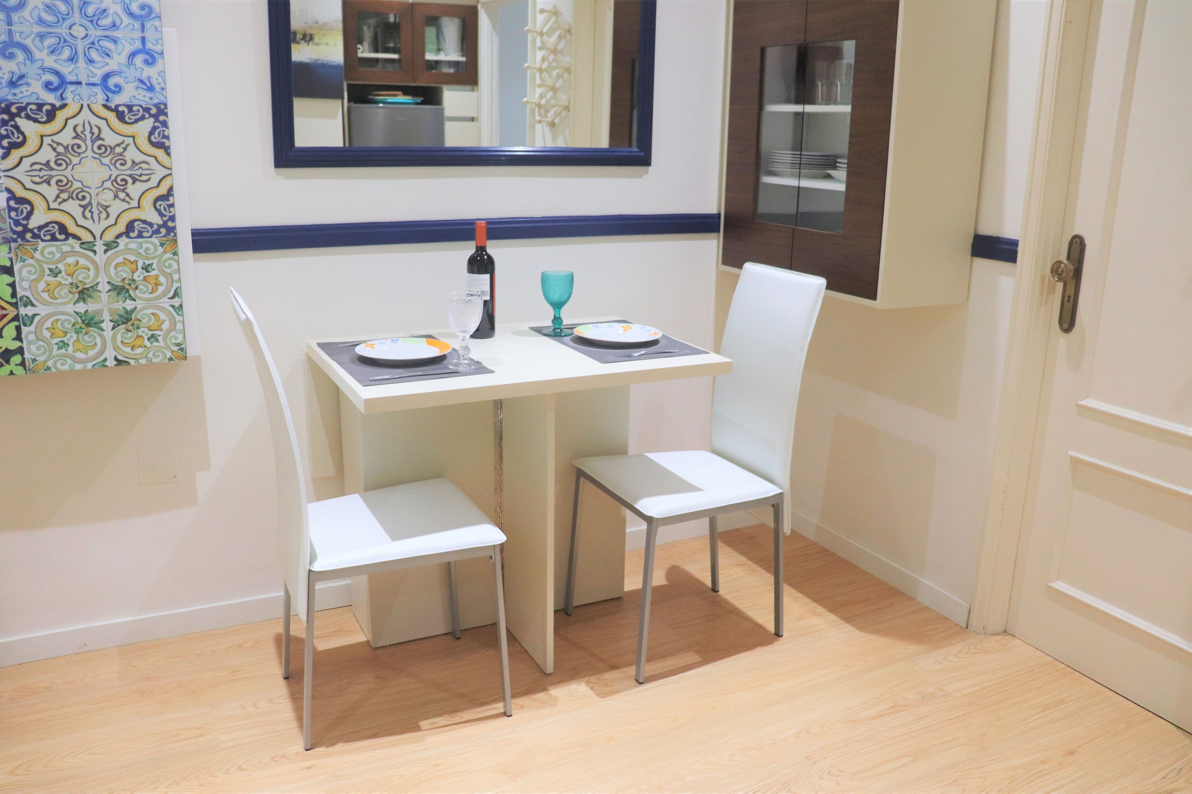 A small dining area with a table and two chairs, a wine bottle, and a glass on the table.
