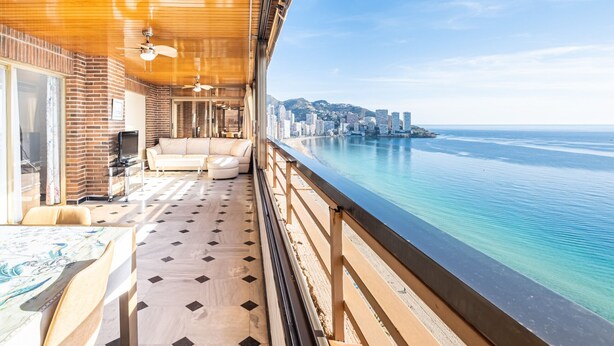 A balcony with a wooden ceiling, a sofa, and a dining table. - Principado Arena 18-A Levante Beach (Benidorm)