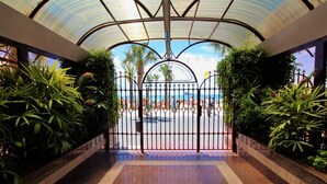 A gated entrance with a view of a beach and palm trees. - Principado Arena 18-A Levante Beach (Benidorm)