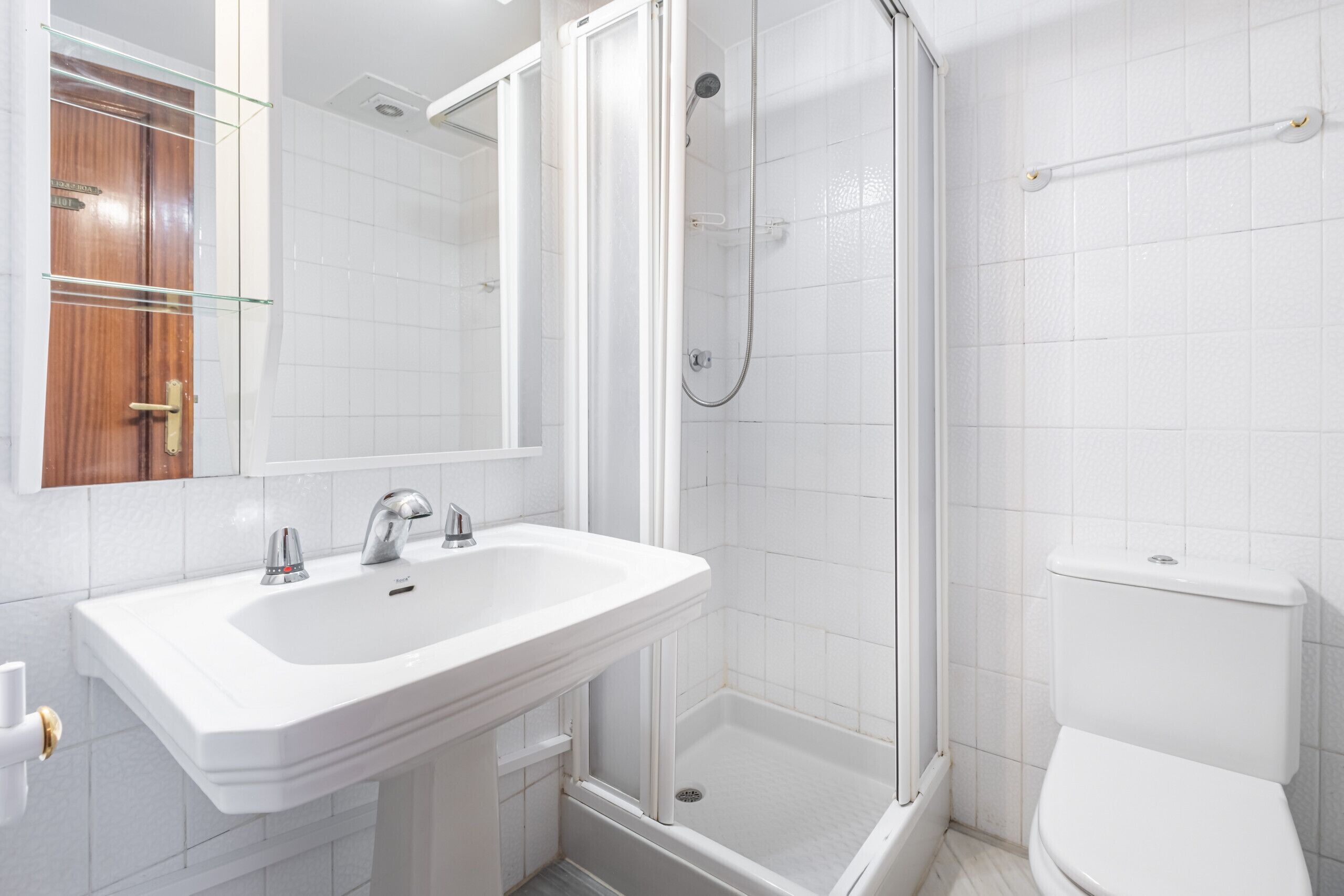 A modern bathroom with a white sink, mirror, and toilet.