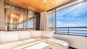 A modern living room with a large white sectional sofa, a small white table, and a view of the ocean through large windows. - Principado Arena 18-A Levante Beach (Benidorm)