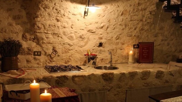 A stone-walled kitchen with a gas stove, sink, and candles. - Superior Apartment (1 person) Residence La Torre (Santo Stefano di Sessanio)