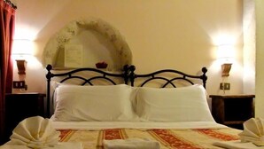 A bed with a headboard, two bedside tables, and a wall-mounted mirror. - Superior Apartment (1 person) Residence La Torre (Santo Stefano di Sessanio)