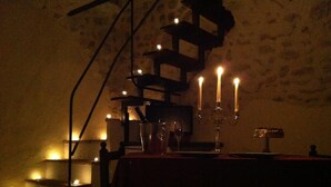 A dimly lit room with a table set for dining, candles, and a decorative metal structure. - Superior Apartment (1 person) Residence La Torre (Santo Stefano di Sessanio)