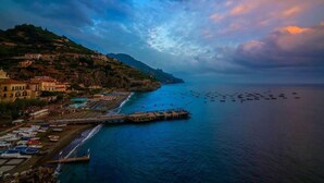 A coastal town with a pier extending into the sea, boats docked along the shore, and buildings on a hillside. - Vicaria, Sea View, a few steps from beach by AMALFIVACATION.IT (Minori)