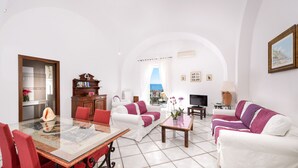 A spacious living room with a glass dining table, white sofas, and a view of the sea. - Vicaria, Sea View, a few steps from beach by AMALFIVACATION.IT (Minori)