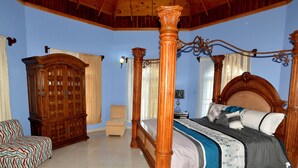 Un dormitorio con cama con dosel, muebles de madera y pared azul.