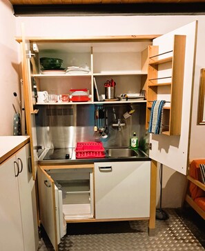 Une cuisine de taille réduite, équipée d’un évier, d’un petit réfrigérateur et d’un four à micro-ondes.