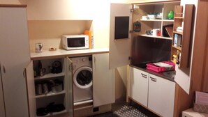 A compact kitchenette with a microwave, a washing machine, and a small refrigerator. - Studio on two floors in an XVIII century building, just 500m from Duomo Square (Milano)
