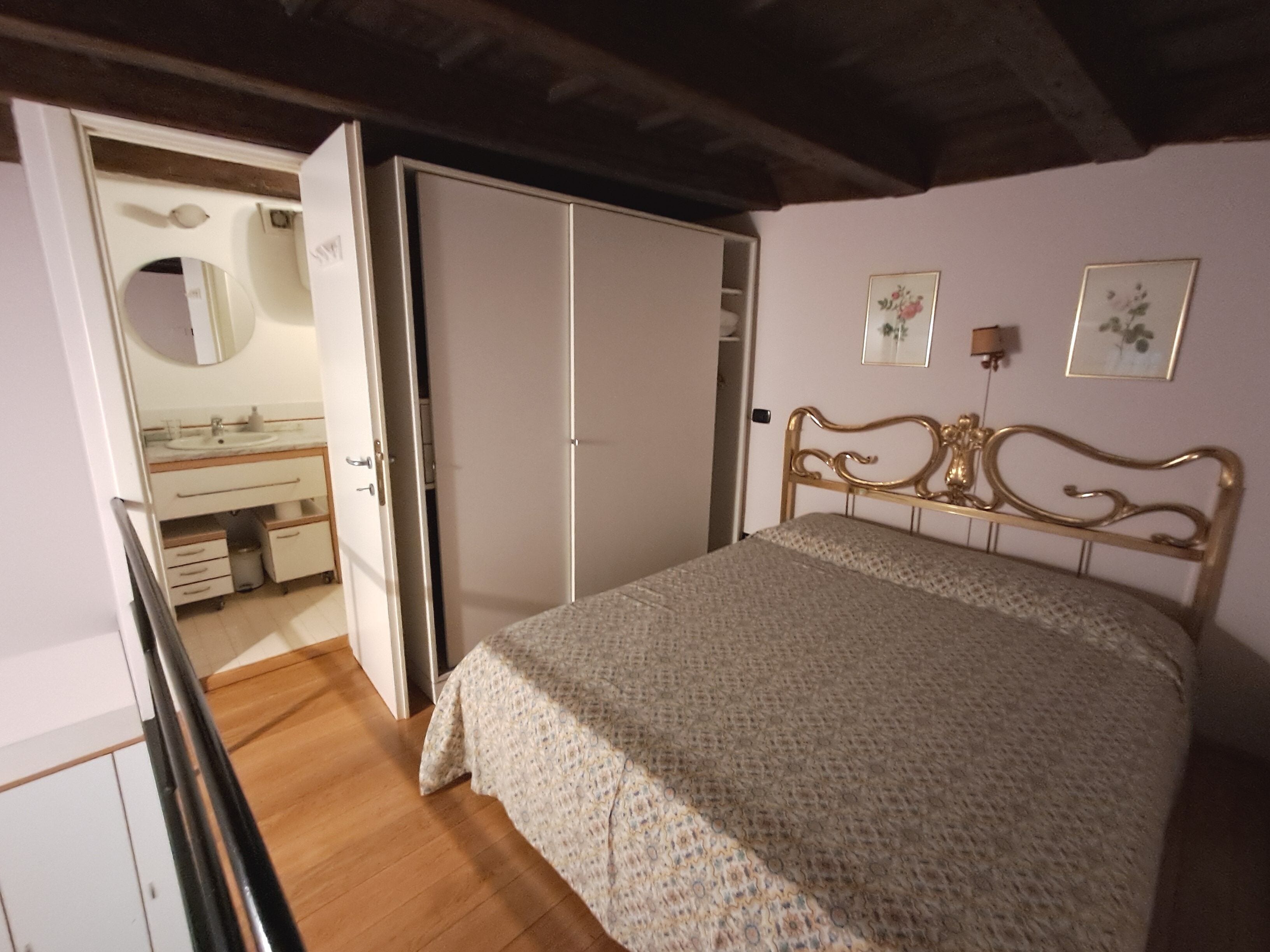 Une chambre à coucher comprenant un lit, une armoire, un miroir et une salle de bain avec un lavabo.