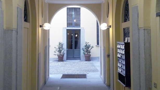 A corridor with an arched ceiling, potted plants, and a door with a sign. - Studio on two floors in an XVIII century building, just 500m from Duomo Square (Milano)