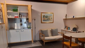 A compact kitchen with a built-in sink, a wooden cabinet, and a dining area with a round table and chairs. - Studio on two floors in an XVIII century building, just 500m from Duomo Square (Milano)