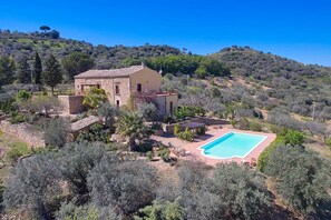 Een villa in mediterrane stijl met een gevel van natuursteen, een zwembad en een weelderige tuin.