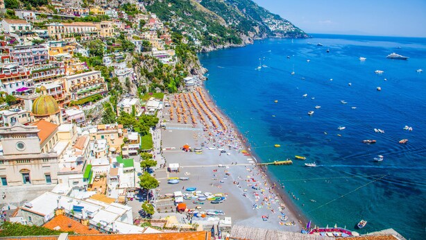 Une ville côtière avec une plage, des bateaux et des bâtiments aux couleurs vives.