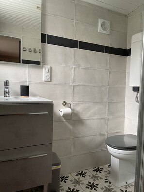 A bathroom with a toilet, sink, and a towel dispenser. - Le Cottage, a house with a garden located 300 meters from the beach (Saint-Palais-Sur-Mer)
