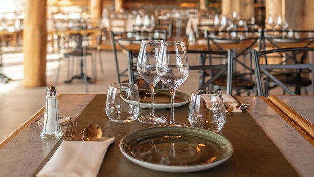 A wooden interior with tables set for dining, featuring clear glassware and plates. - Hôtel des Pyrénées (Font-Romeu-Odeillo-Via)
