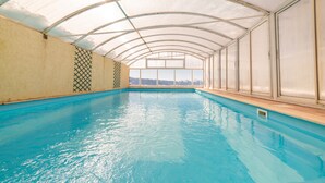 An indoor swimming pool with a glass ceiling and a view of mountains. - Hôtel des Pyrénées (Font-Romeu-Odeillo-Via)