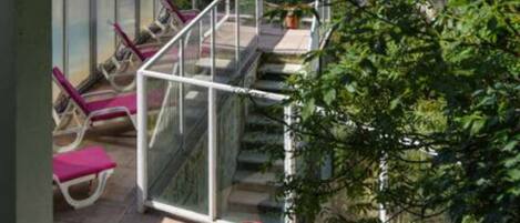 Un balcon doté d’une balustrade en verre, offrant une vue sur un paysage montagneux.