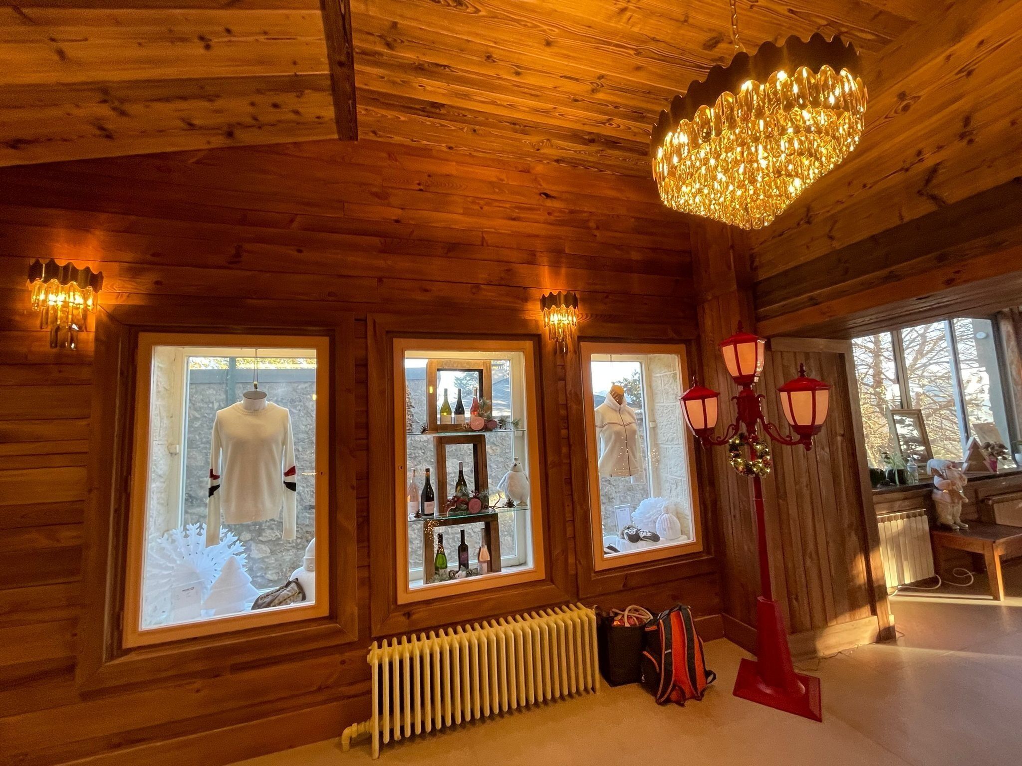 Interior de madera con ventanas amplias, un radiador y una araña.