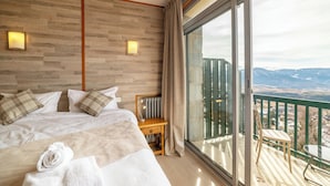 A hotel room with a large bed, a wooden headboard, a desk with a lamp, and a balcony with a view of mountains. - Hôtel des Pyrénées (Font-Romeu-Odeillo-Via)