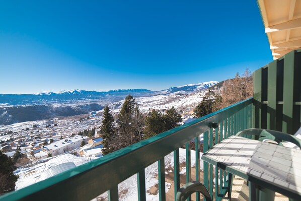 Un balcón con vistas a un pueblo nevado y montañas.